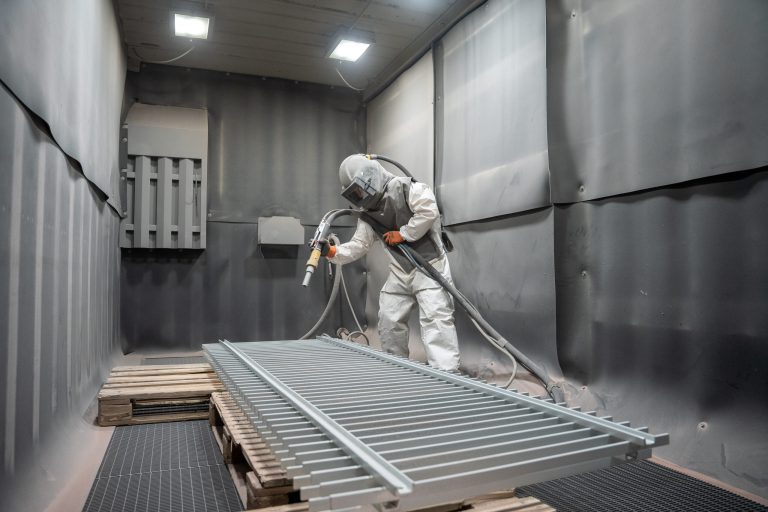 Mitarbeiter beim Sandstrahlen eines Gitterrosts in der Strahlkabine