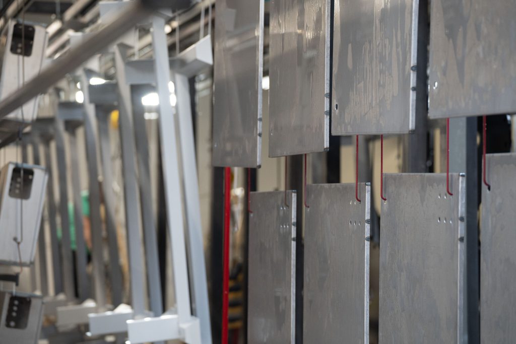 Bauteile hängend an der Pulverbeschichtungsanlage